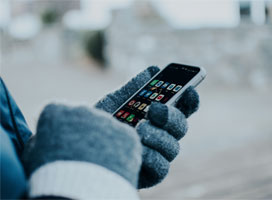 Person wearing mittens, holding cell phone
