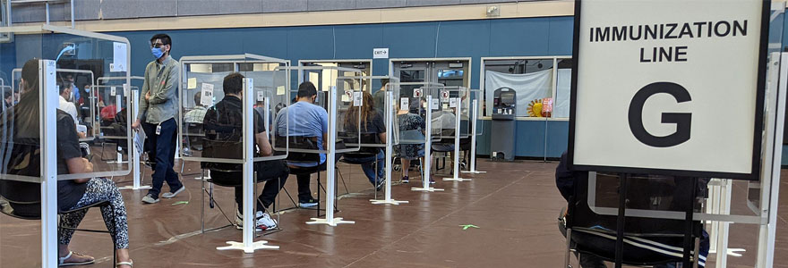 COVID-19 immunization line inside the Guildford Recreation Centre in Surrey, British Columbia, Canada. Photo by Northwest via Wikimedia Commons (CC BY-SA 4.0)