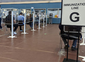 COVID-19 immunization line inside the Guildford Recreation Centre in Surrey, British Columbia, Canada. Photo by Northwest via Wikimedia Commons (CC BY-SA 4.0)