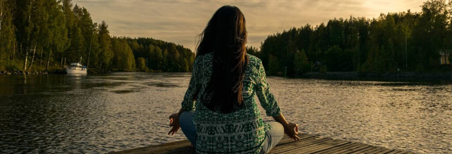 Woman sits on dock, meditating. Photo by leninscape, from Pixabay 