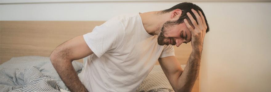 Man sitting on bed, in pain